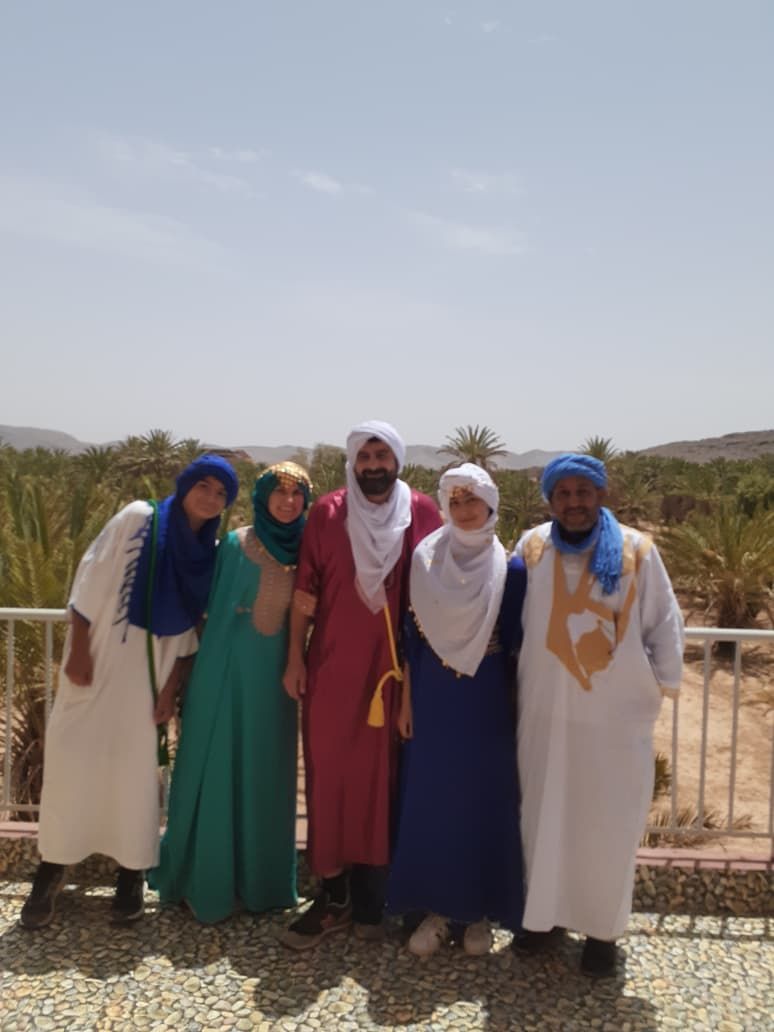 Family in traditional Moroccan dress by the palm oasis